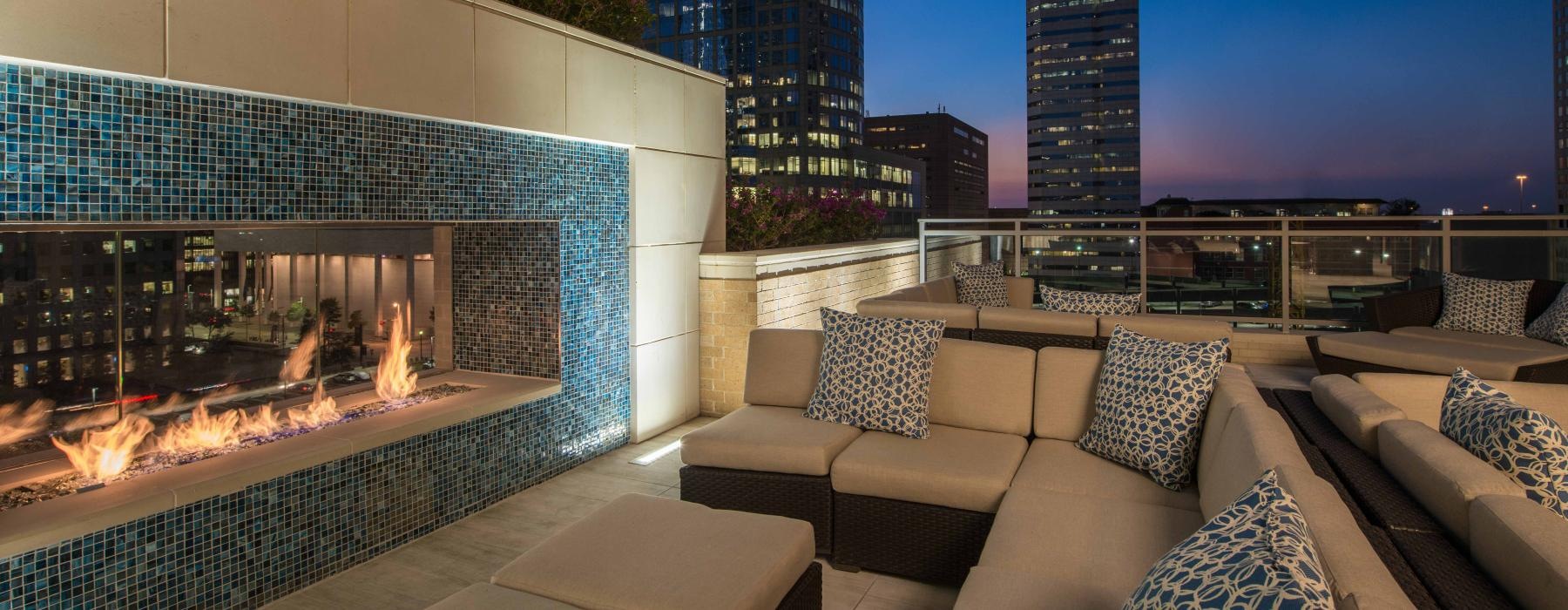 a room with a large glass wall and a large pool with a city skyline in the background